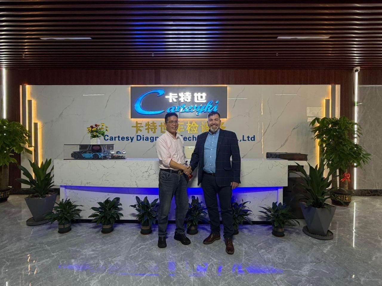 Joe from Transport Solutions shaking hands with a Cartesy executive in front of the Cartesy factory reception.